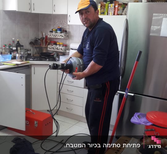 אדם מחזיק מכשיר אינסטלציה במטבח